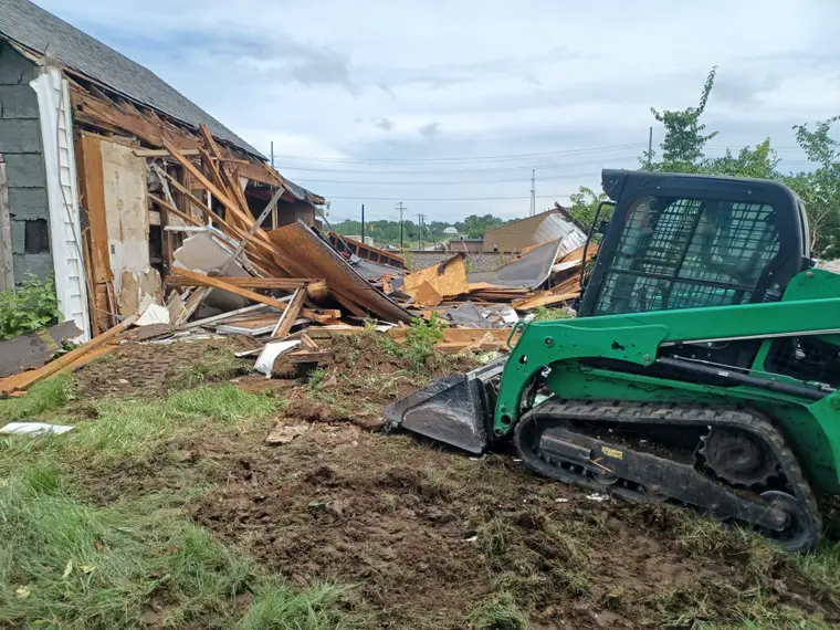 Skid steer clearing a demolished structure in Dayton, Ohio